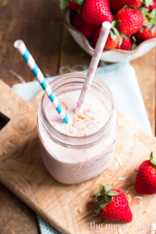 Strawberry Coconut Smoothie in a mason jar with two straws. 
