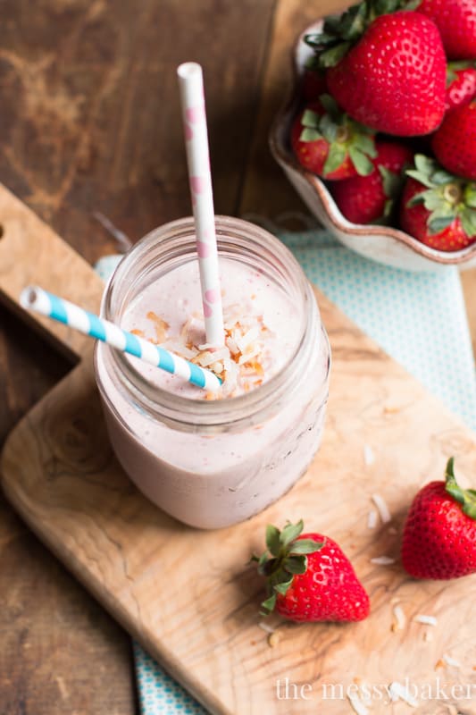 Strawberry Coconut Smoothie in a mason jar with strawberries on the side. 