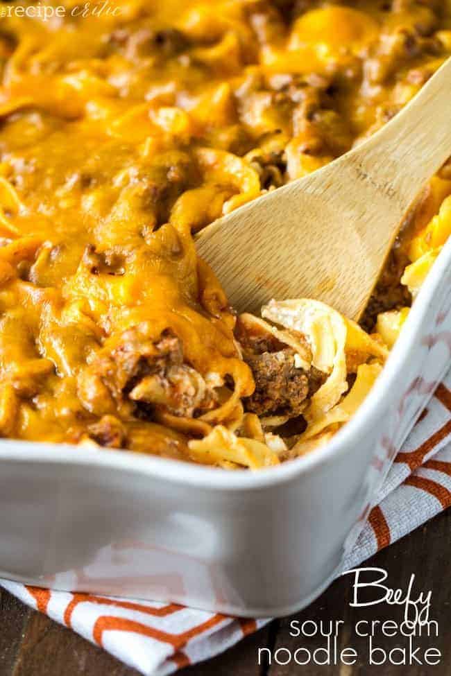 Beefy Sour Cream Noodle Bake in a white casserole dish with a wood spoon. 