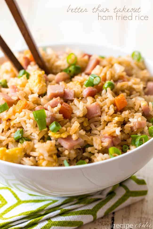 Ham fried rice in a white bowl with a wood spoon. 