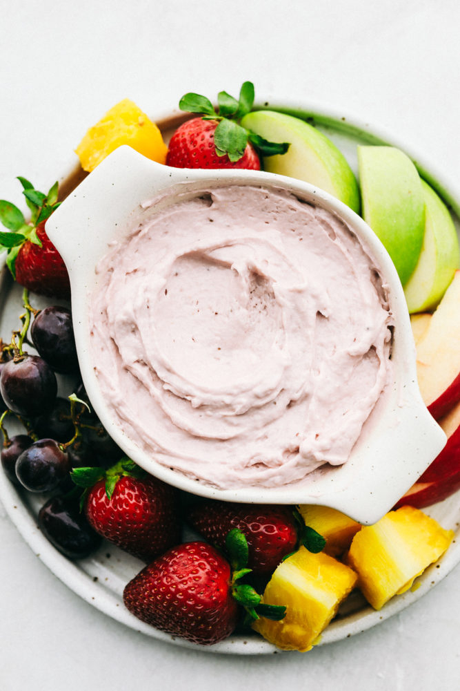 Strawberry Cream Cheese Fruit Dip in a white dish with fresh fruit and berries on the side to dip. 