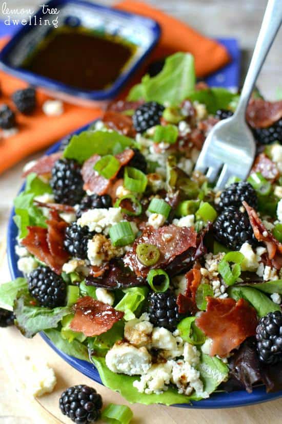 Blackberry, Bacon & Blue Cheese Salad in blue bowl with a metal fork. 