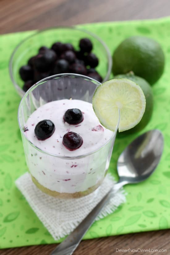 Blueberry Lime No-Bake Cheesecake Cup with fresh lime and blueberries and a metal fork on the side. 