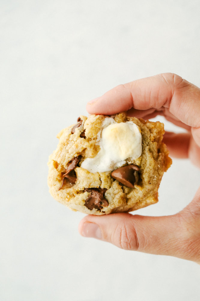 Gooey s'mores cookie being held up by a hand. 