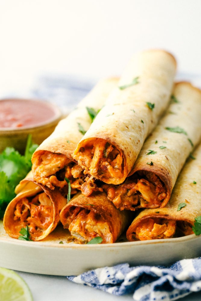 Chicken taquitos stacked on top of each other on a plate. 