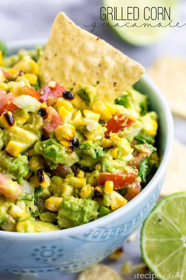 Grilled corn guacamole in a bowl with a chip on the side. 