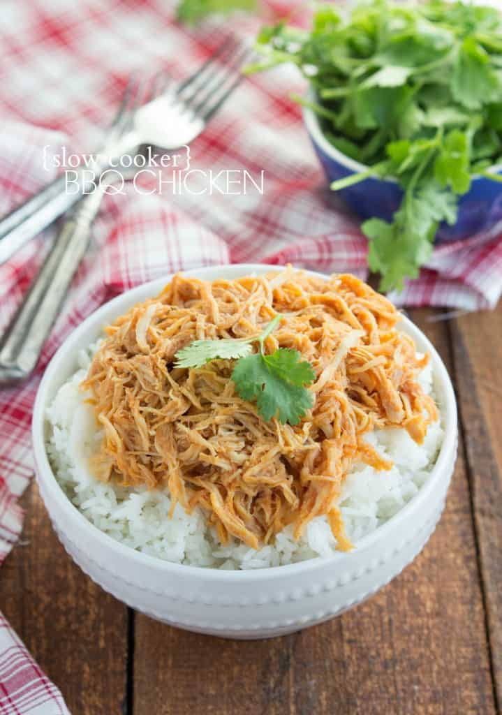 Slow cooker bbq chicken in a white bowl over top of rice. 