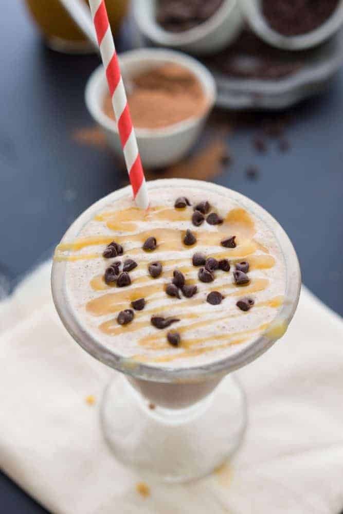 Overhead shot of milkshake and a straw topped with caramel and chocolate chips. 