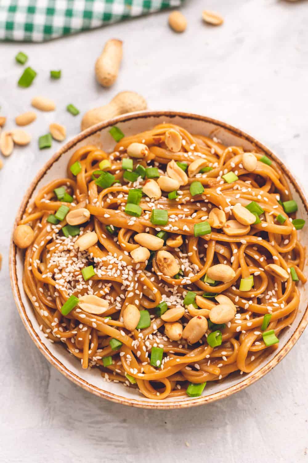 Thai peanut sesame noodles in a bowl with peanuts and onions garnished over top. 