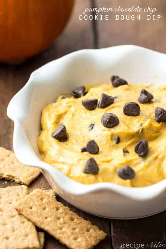 Pumpkin chocolate chip cookie dough dip in a white bowl with graham crackers on the side. 