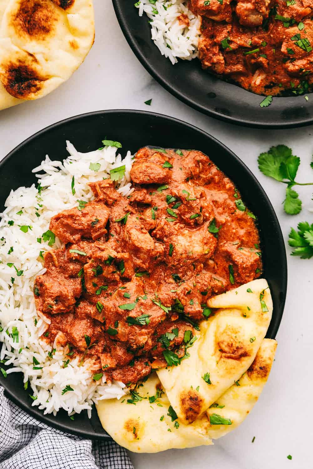 Pollo tikka masala servido en un bol con arroz y pan naan.