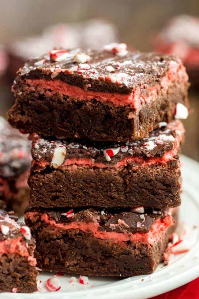 Peppermint chocolate brownies stacked on top of each other on a white plate.