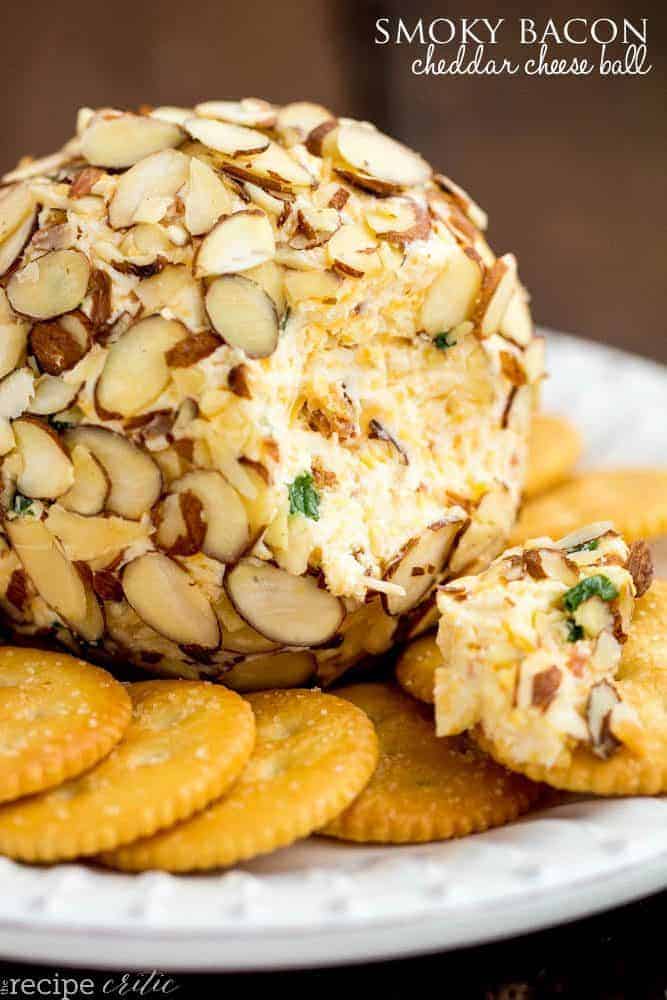 Smoky Bacon Cheddar Cheese Ball on a white plate with crackers on the side. 