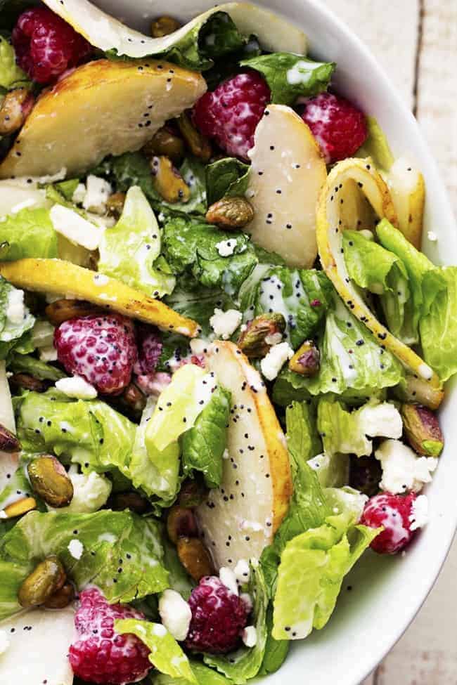 pear raspberry pistachio salad in a white bowl.