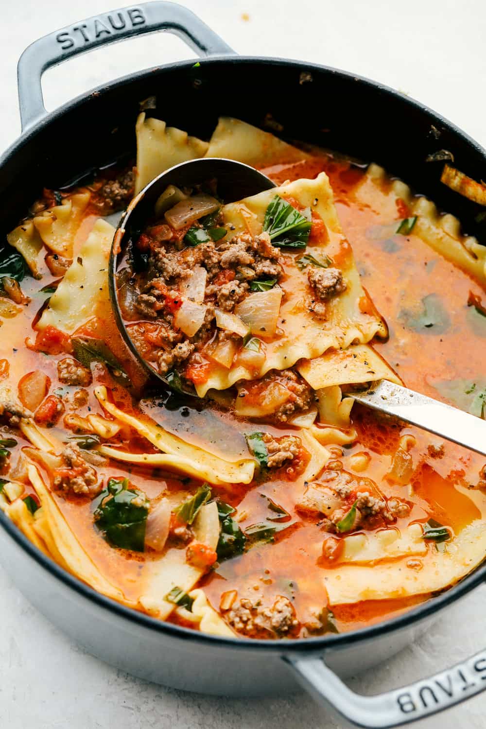 Close up shot of a pot of lasagna soup with a ladle dishing up a scoop.