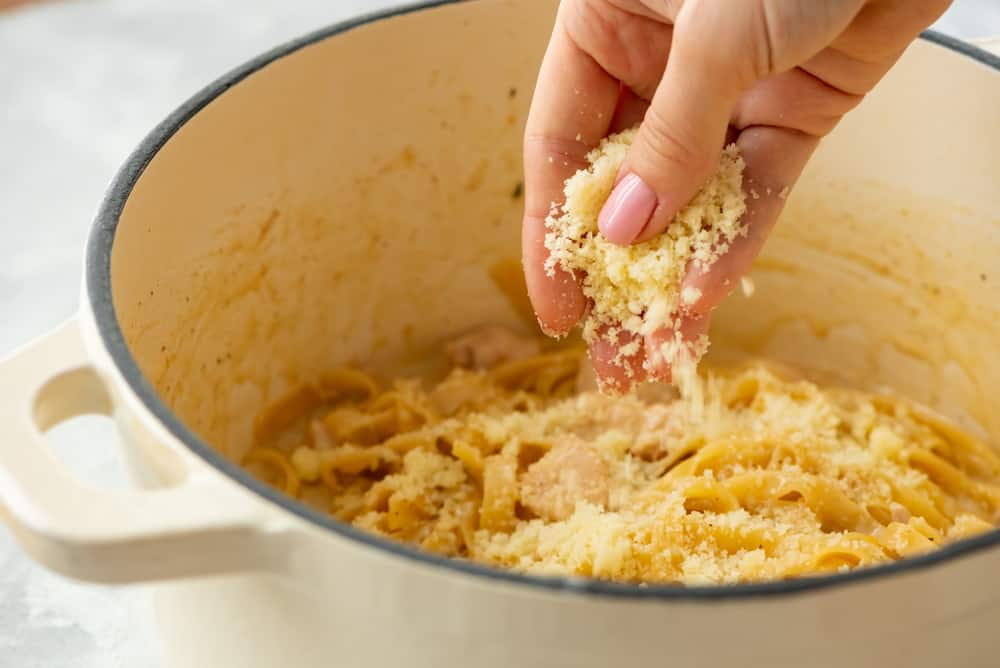 adding cheese to the top of the fettuccine noodles