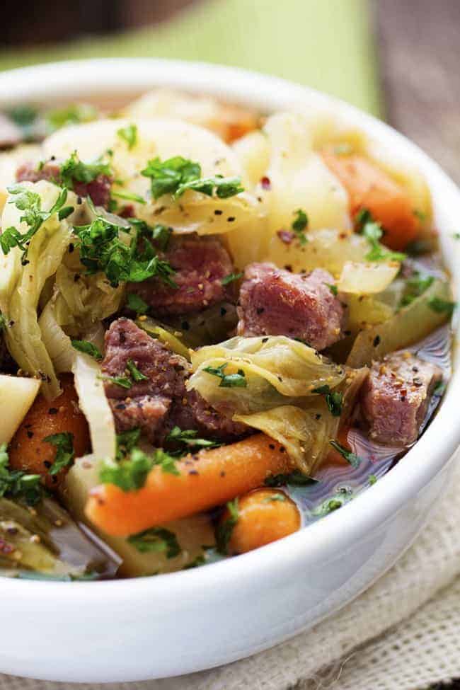 Corned beef cabbage stew in a white bowl.