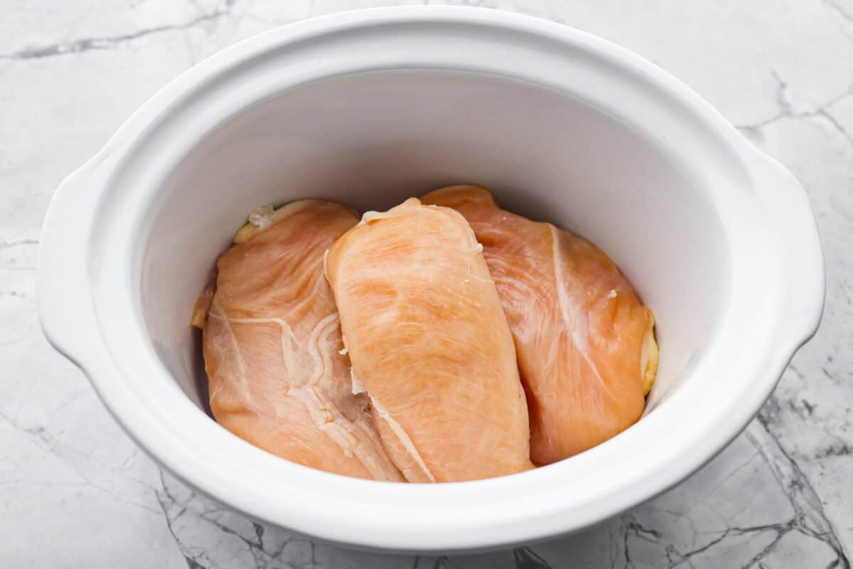 Overhead shot of chicken breasts in the bottom of the crock pot. 