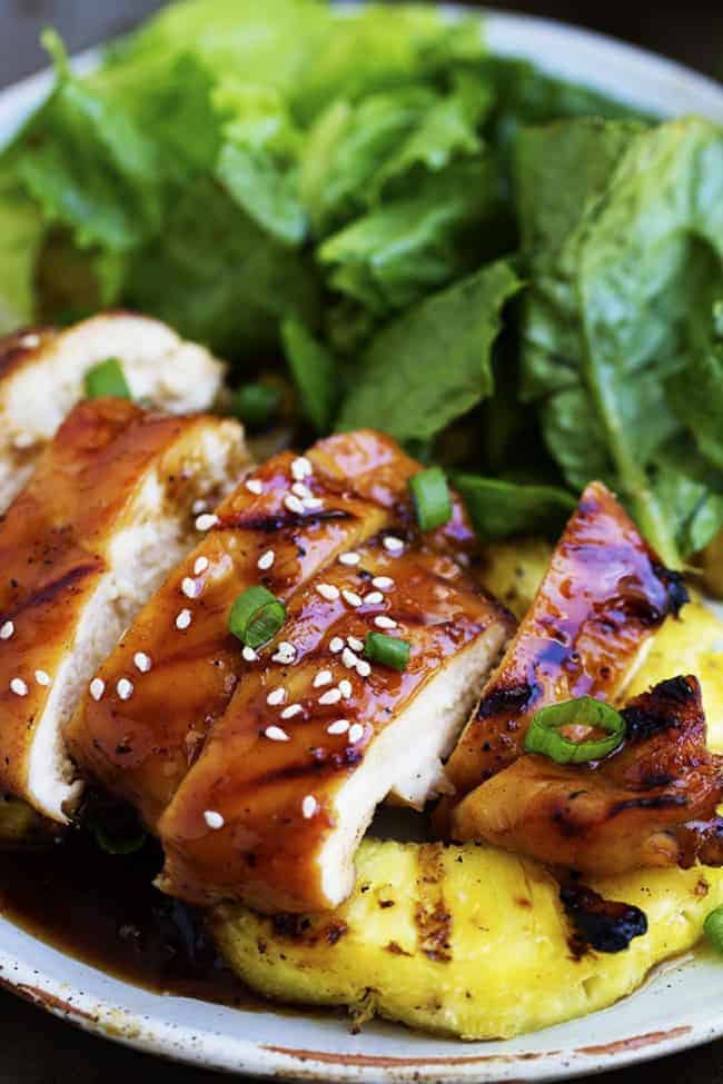 pineapple teriyaki chicken with pineapple and salad on a white plate.