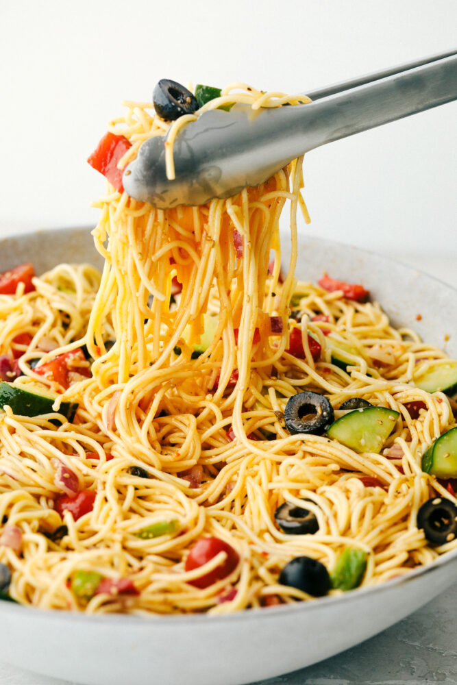California spaghetti salad being lifted by the tongs. 