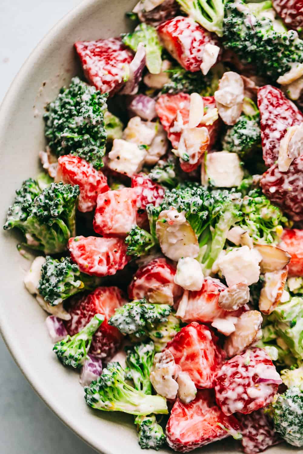 Broccoli Strawberry salad in a white bowl mixed together.