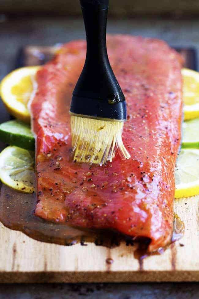 Brushing grilled salmon with sauce.