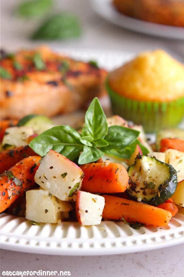 Italian Roasted Veggies on a white plate with cornbread and chicken.