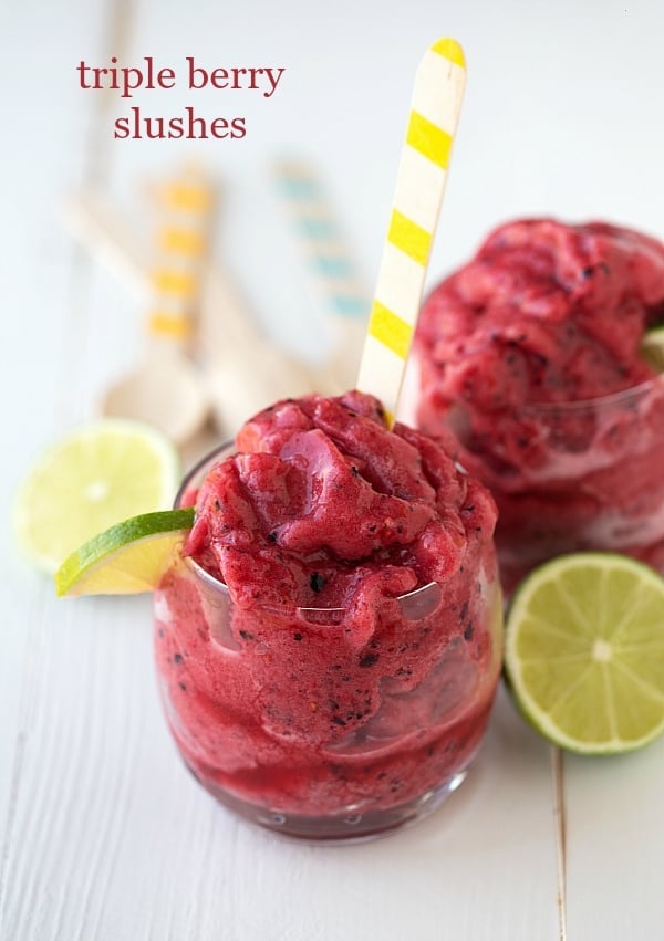 Easy Triple Berry Slushes in glass cups with yellow and white spoons and lime garnish.