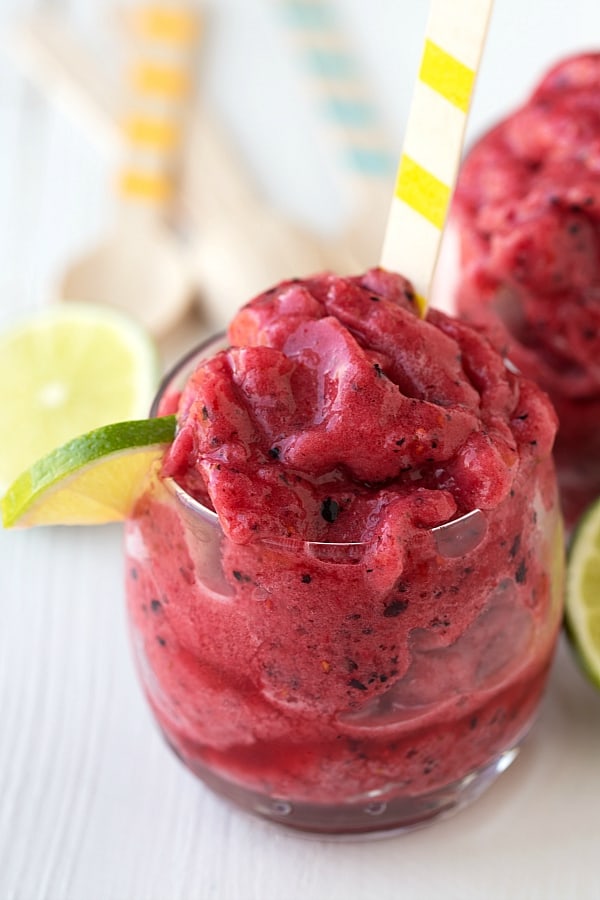 Easy Triple Berry Slush in a white glass with a yellow and white spoon and lime garnish.