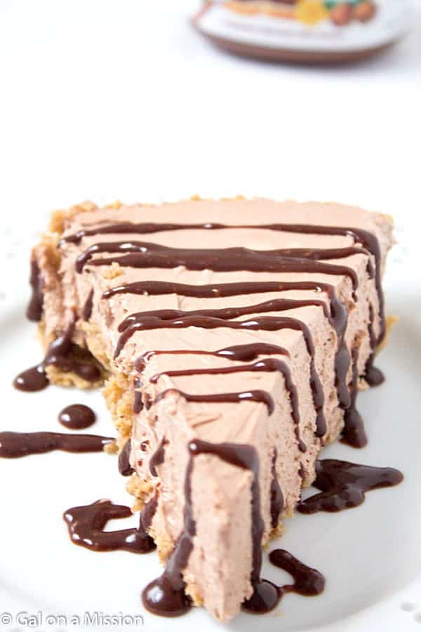 No-Bake Nutella Pie in Großaufnahme auf einem weißen Teller und mit Schokoladensirup beträufelt.