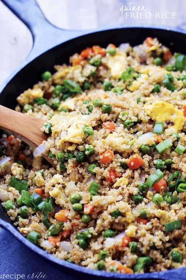 Quinoa fried rice in a skillet with a wooden spoon.