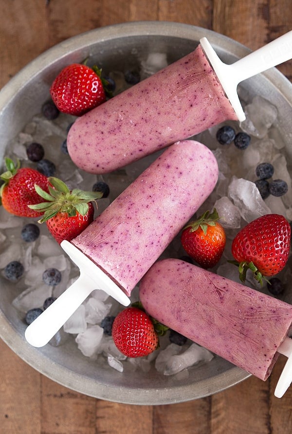 Greek yogurt fruit pops laying on top of a bowl of ice and fruit.