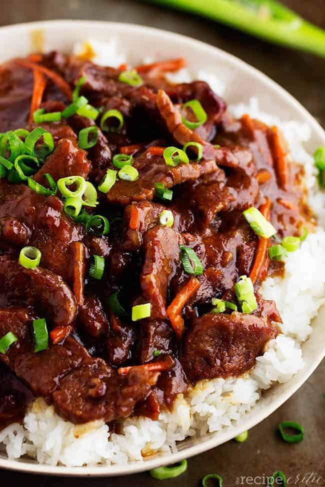 Slow cooker mongolian beef on rice and a white plate.