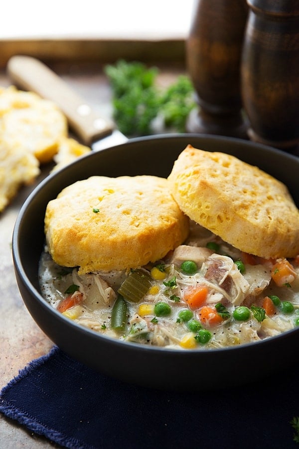 Chicken Pot Pie Soup in a bowl with 2 biscuits on top.