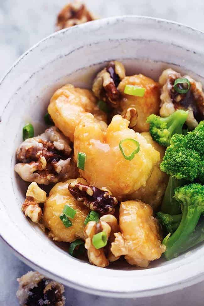 honey walnut shrimp in a white bowl with broccoli.