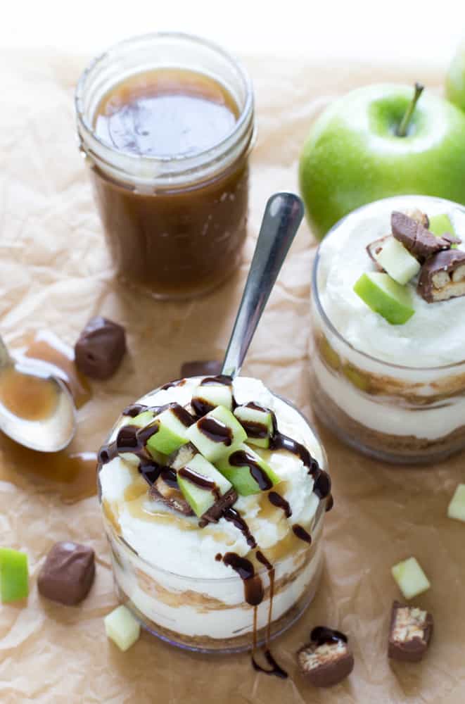 Snickers Caramel Apple Cheesecake in a glass cup with a spoon.