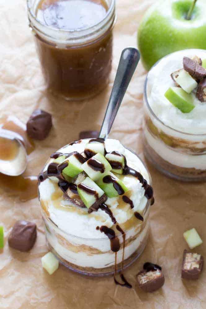 Snickers Cheesecake in a glass cup with a spoon.