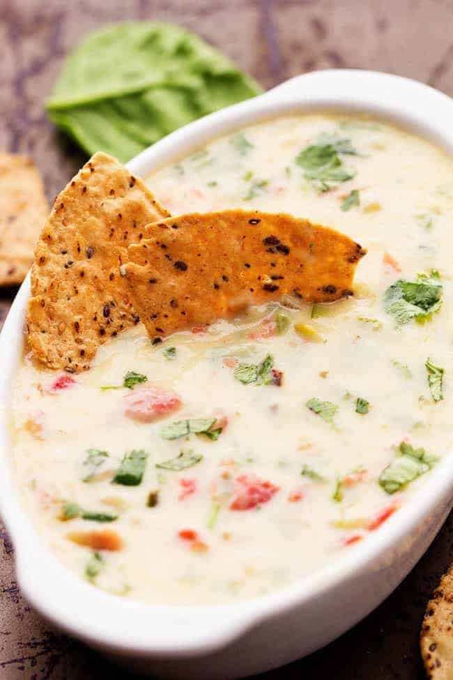 White Spinach Queso in a white serving dish with 2 tortilla chips.