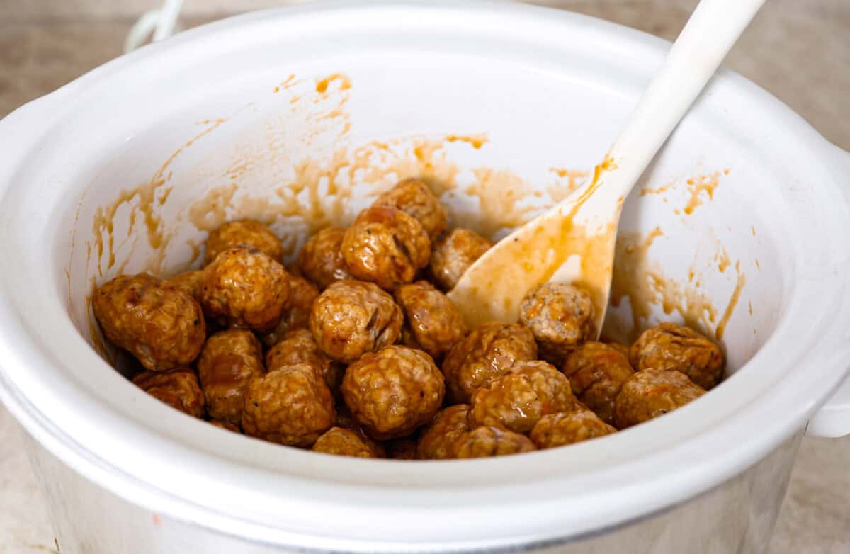 Angle shot of the meatballs mixed with the sauce in the crock pot. 