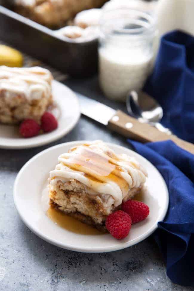 Cinnamon roll biscuit bake on a white plate with raspberry garnish.