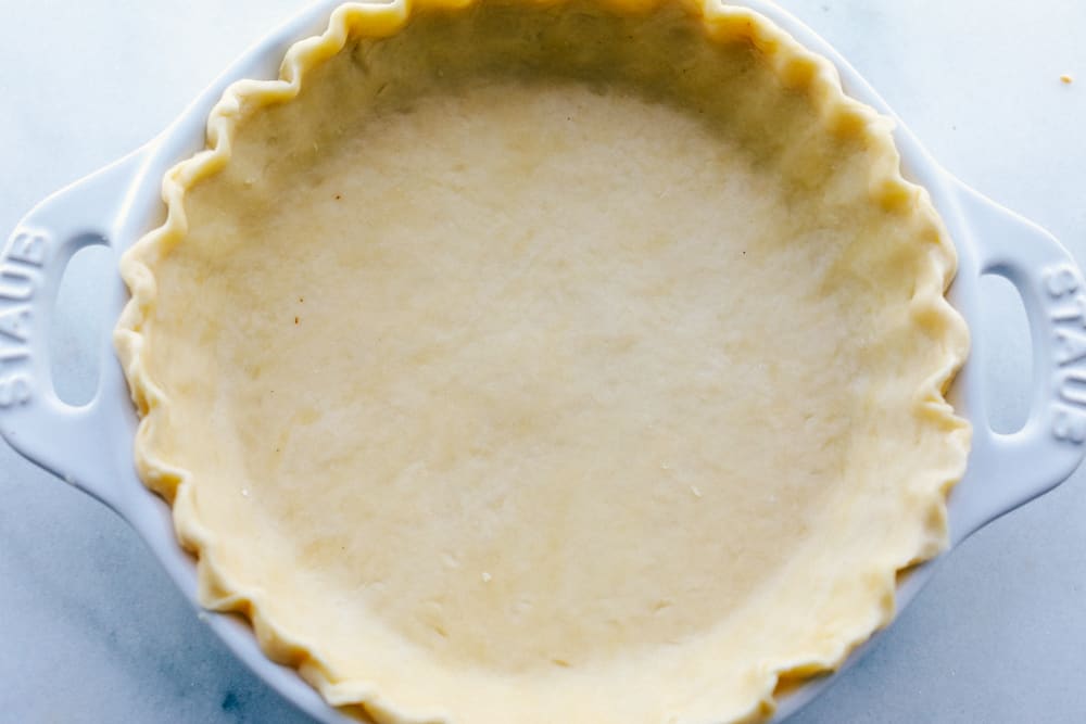 A pie crust that is shaped and ready to be baked. 