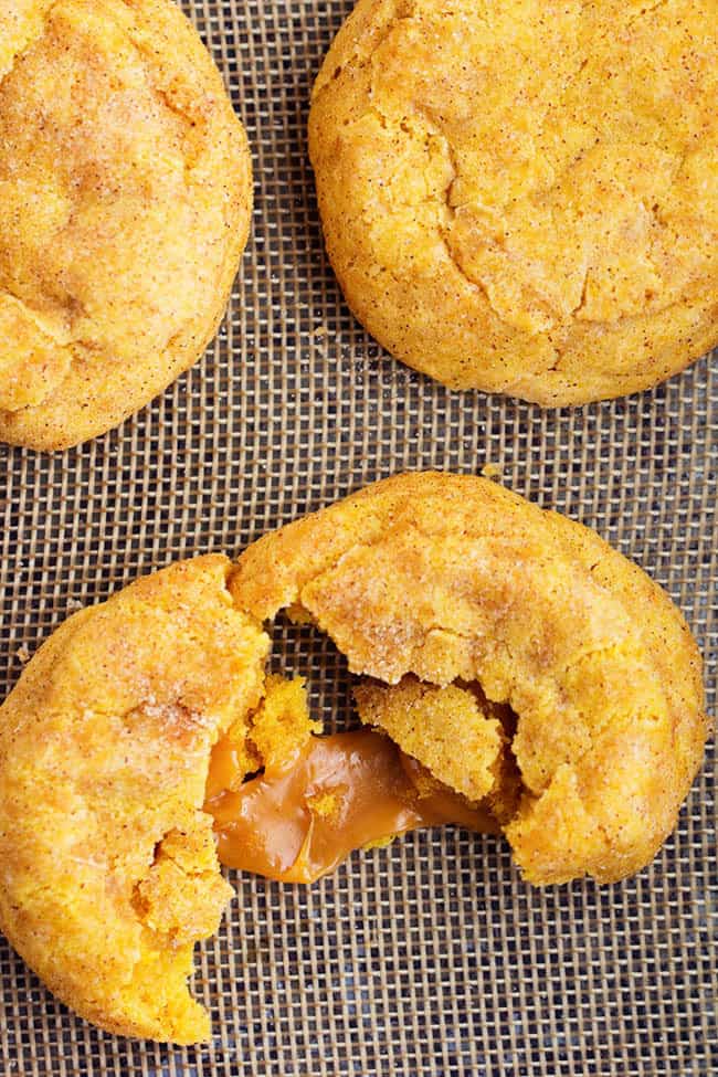 caramel pumpkin snickerdoodle cookies with one cut in half to show gooey inside.