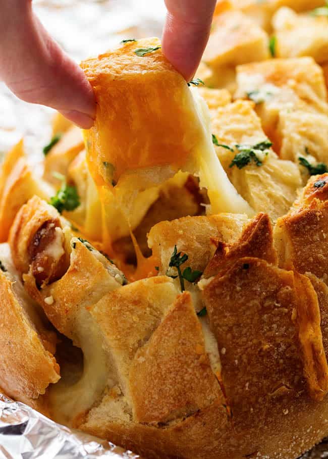 Fingers pulling apart the cheesy bread.