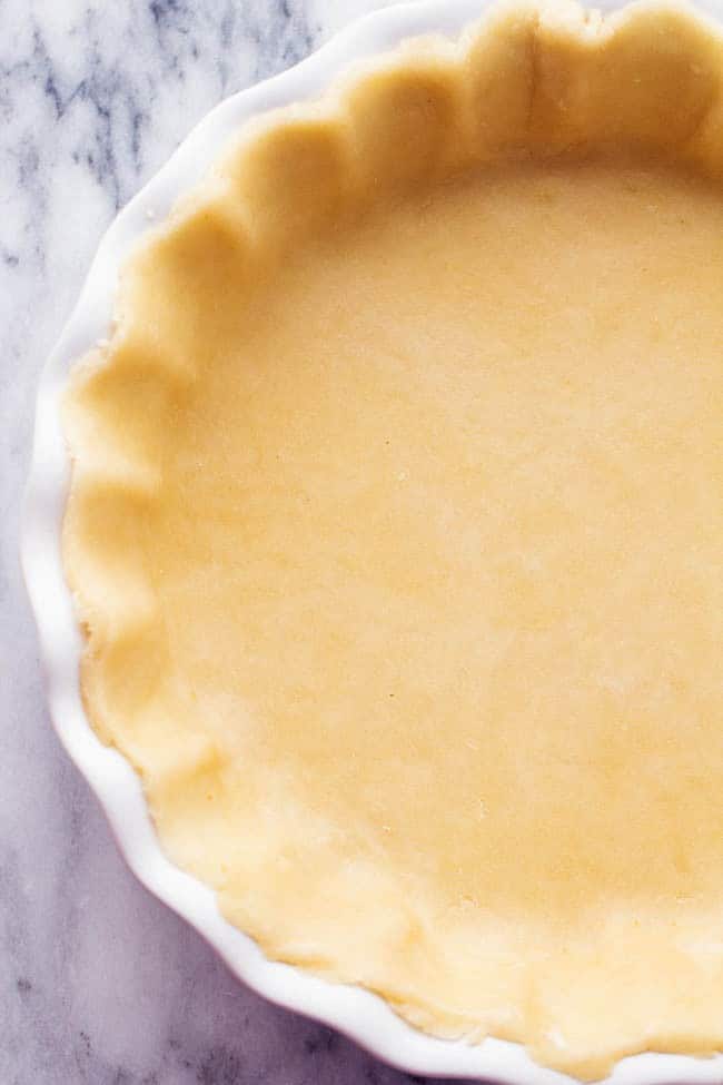 Top-down view of pie crust in white dish.