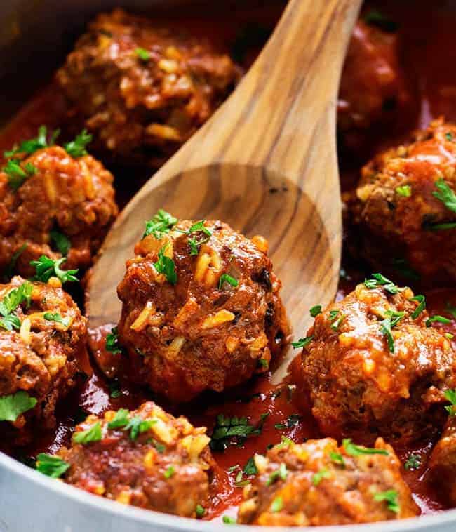 Porcupine meatballs in a skillet with a wooden spoon. 