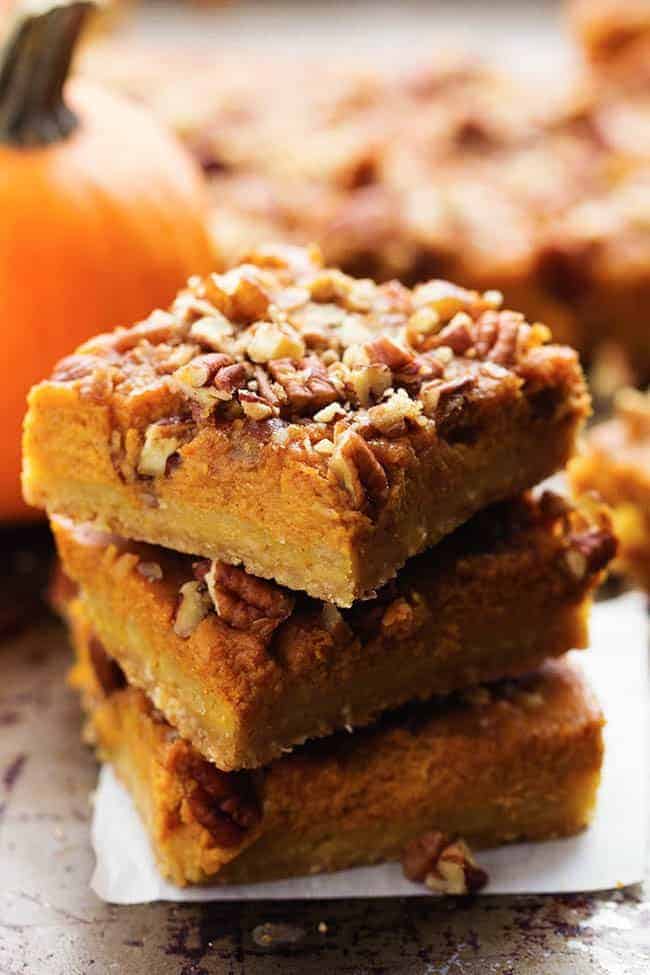 Three pumpkin pecan pie bars stacked on top of each other.