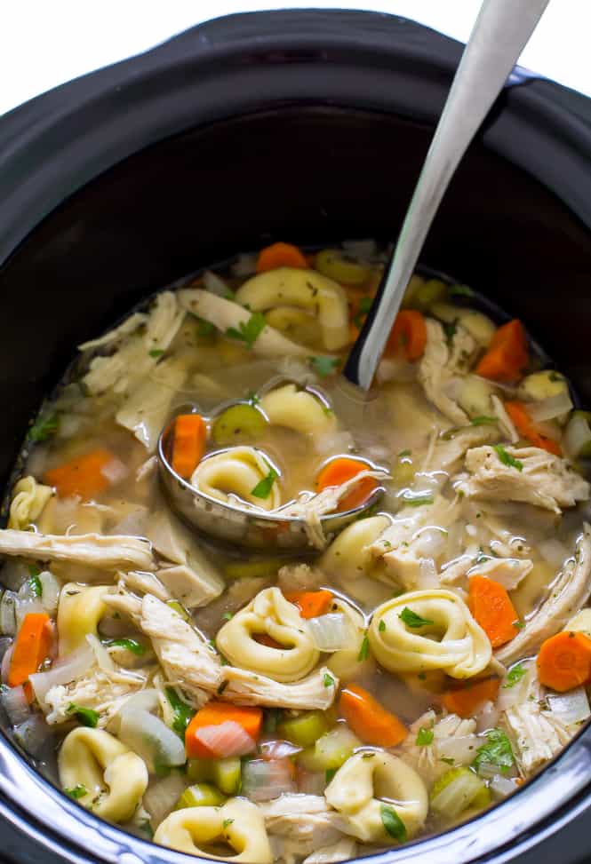 Slow cooker chicken tortellini soup in a slow cooker with ladle 