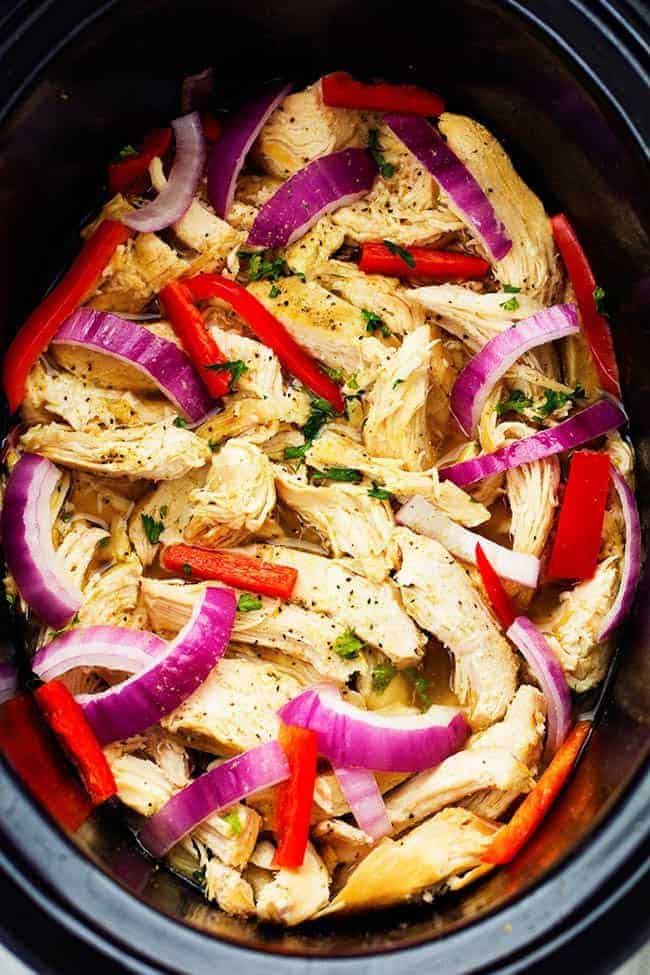 Chicken in a slow cooker with peppers and onions.