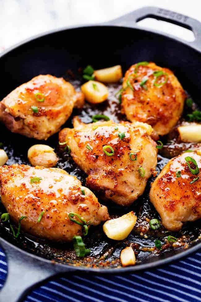 Chicken in frying pan with garlic and onion.