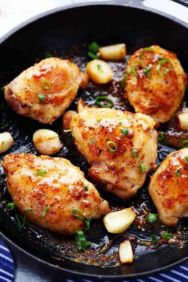 Chicken in a frying pan with garlic and onion.